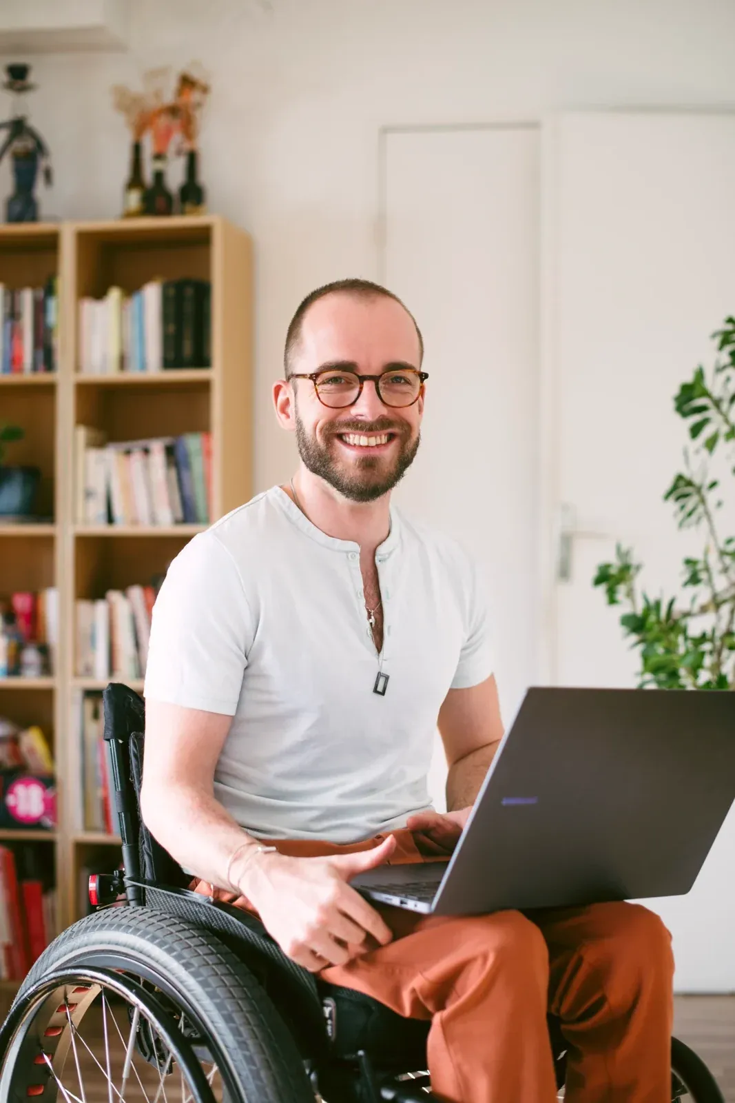 Paul Mallet, souriant dans son fauteuil roulant, son ordinateur sur les genoux.